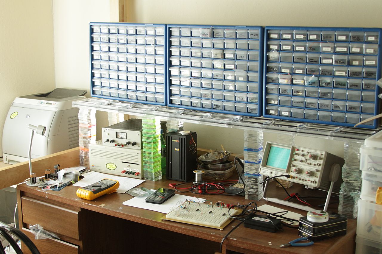 An electronics soldering workbench with iron, magnifier, and components